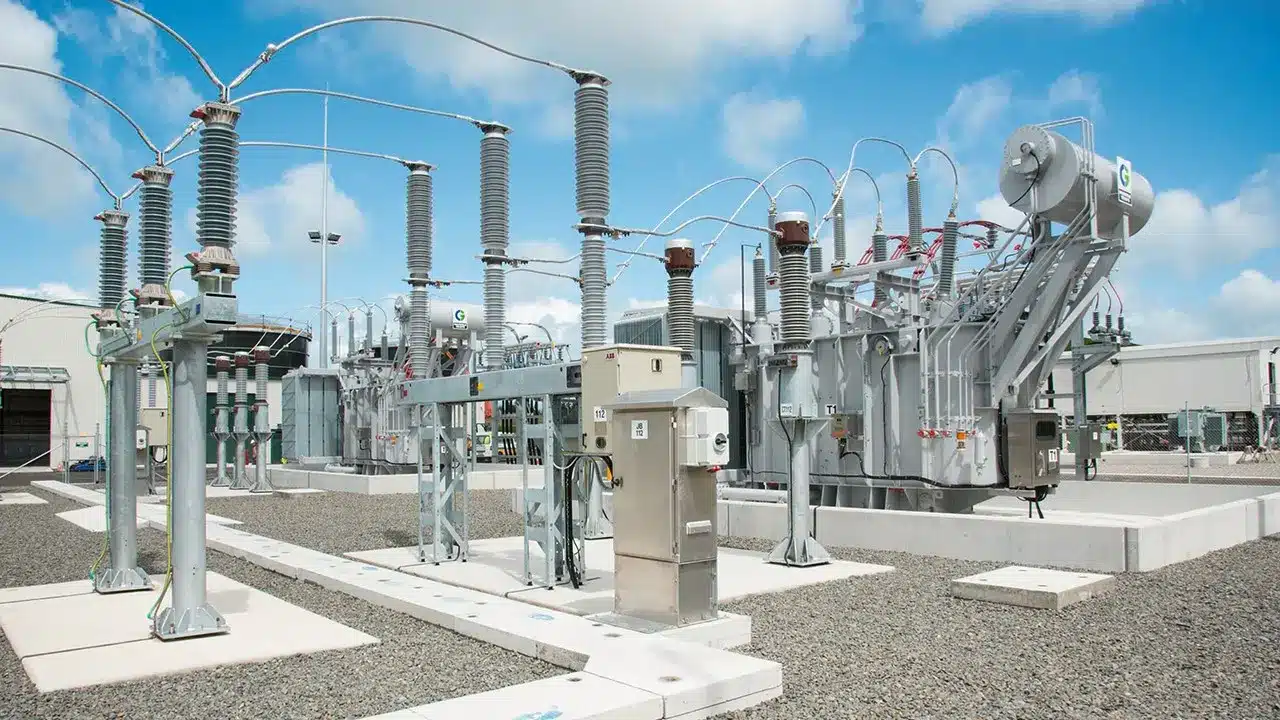 High voltage electrical substation with transformers, insulators, and wiring on a gravel lot